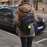Gājēja ar atstarotāju pie somas tumšā laikā uz ielas